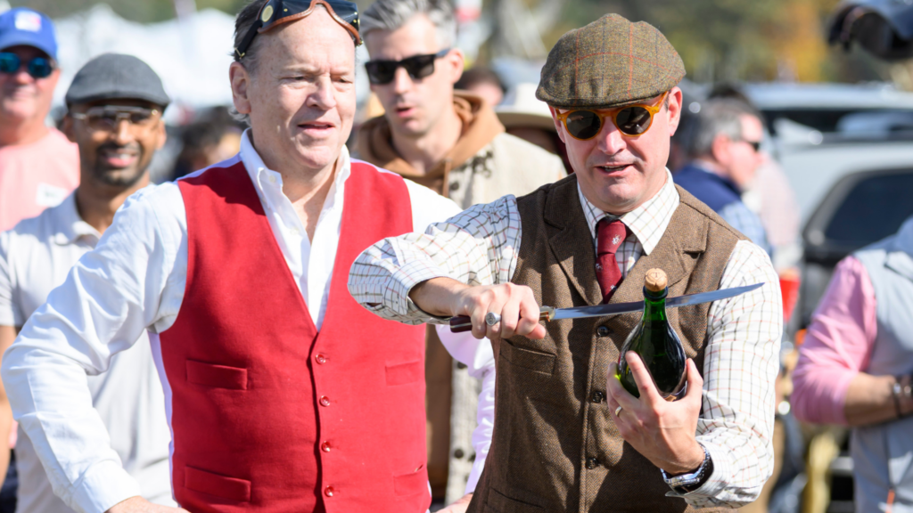 Far Hills Race Meeting guest in classic tweed vest, flat cap and tie opening champagne during the fall steeplechase event.
